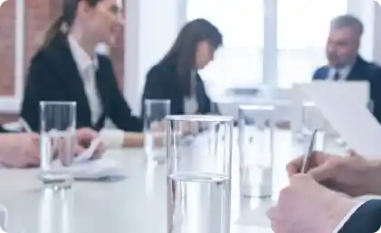 meeting table with glasses of water and business people